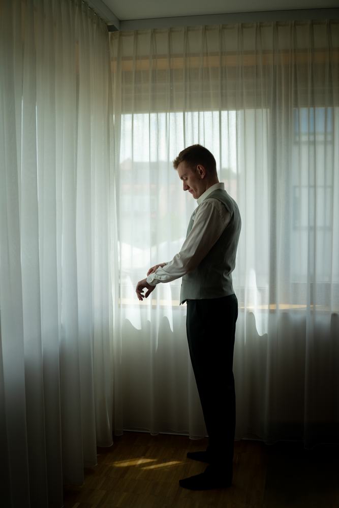 Groom getting ready by a bright window