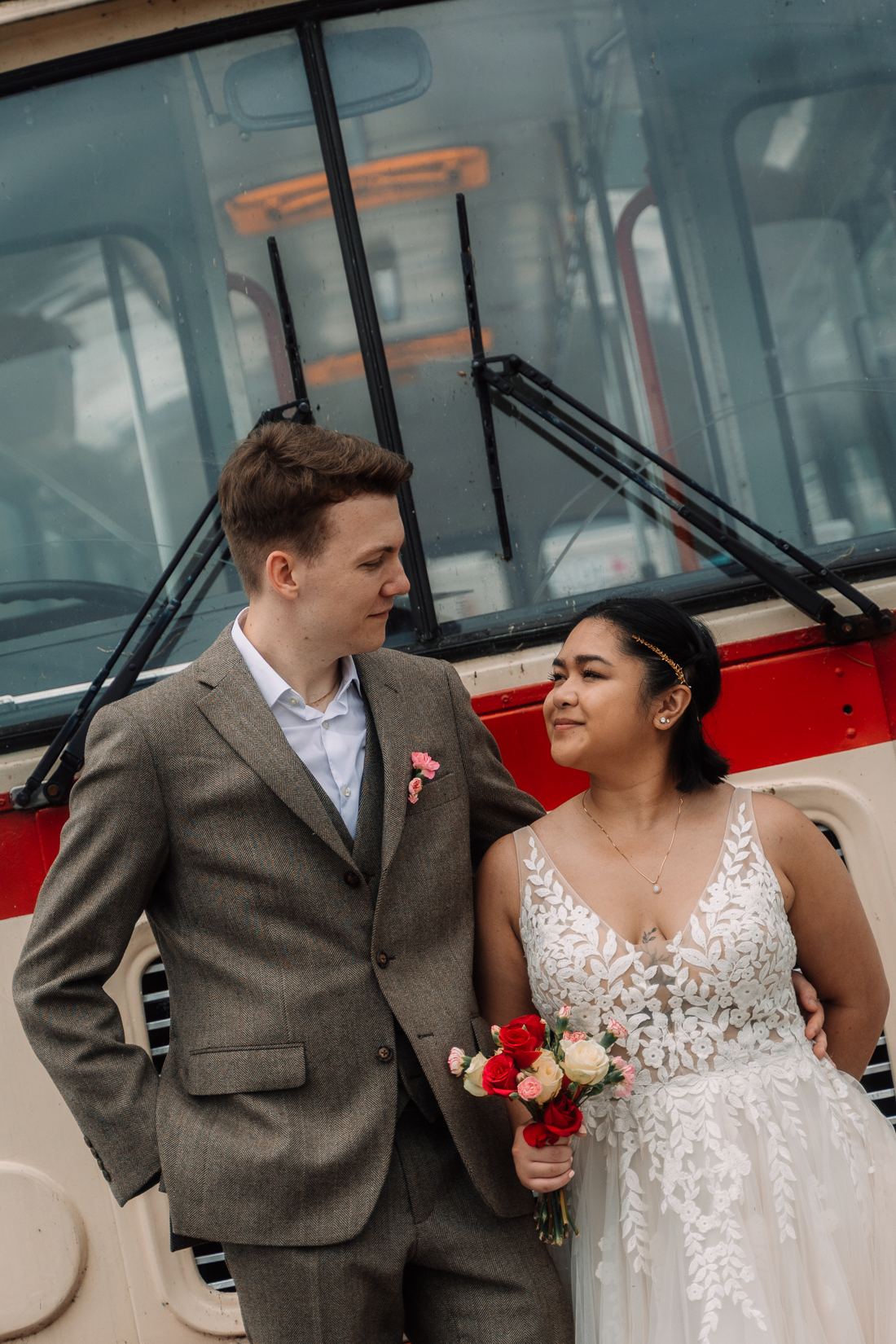 Bride and groom in front of a vintage red and cream bus