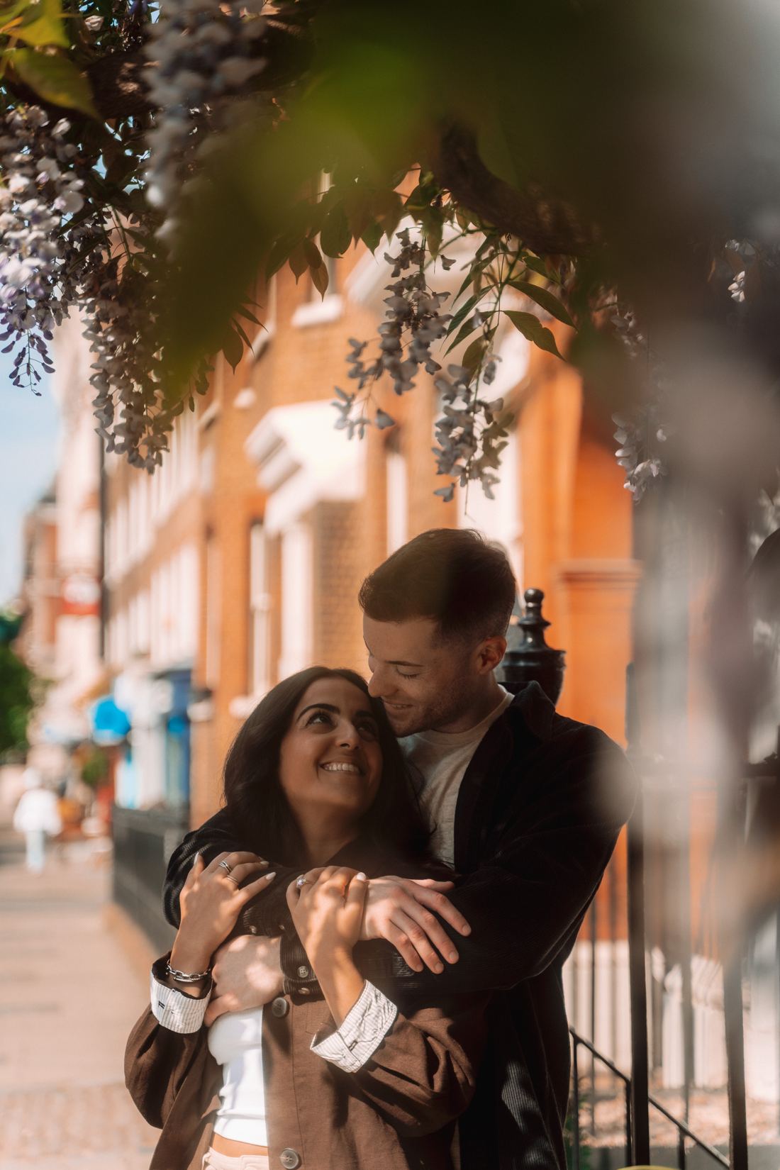 Couple embracing under wisteria, both smiling