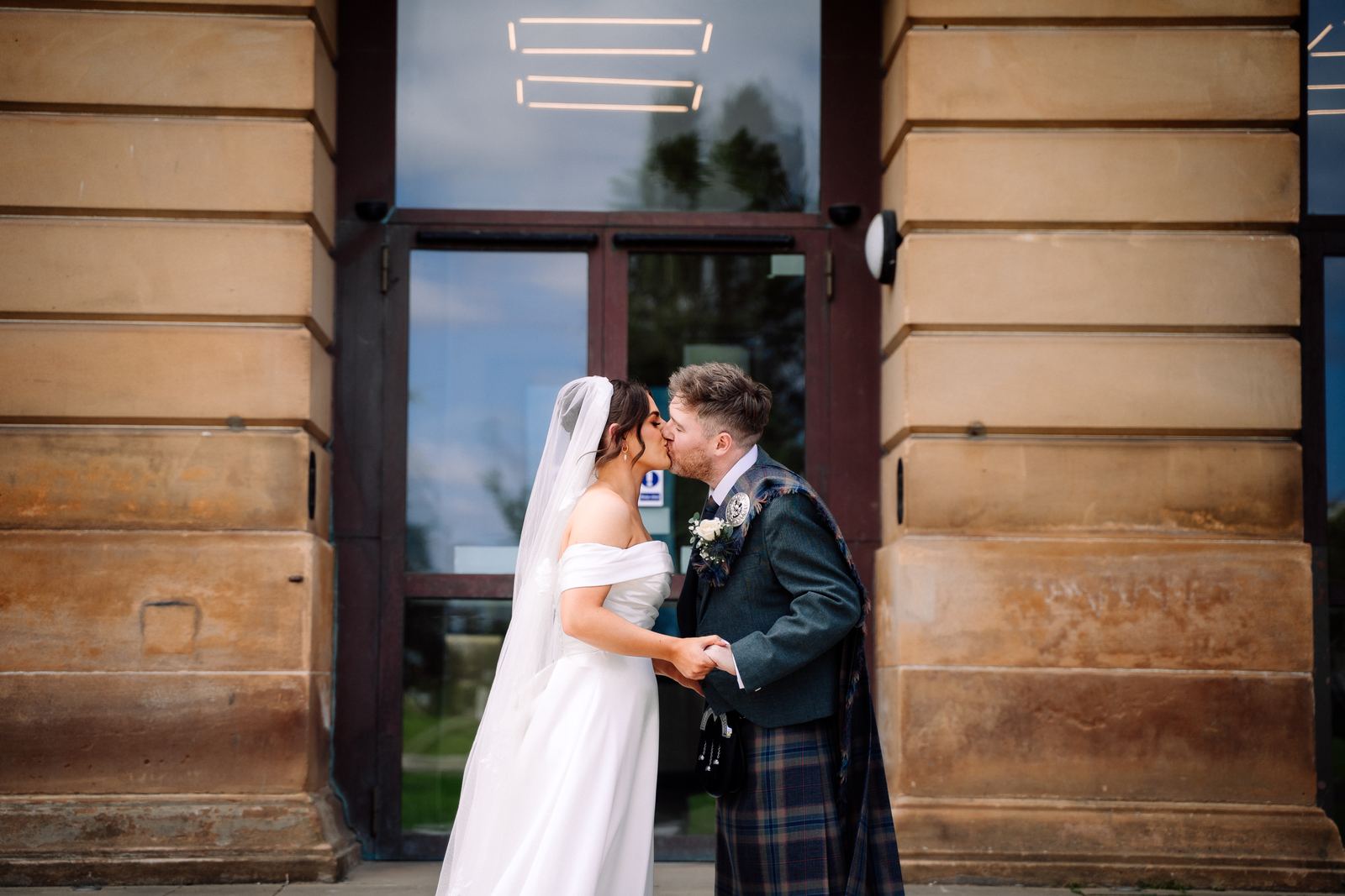Newlyweds kissing in a sandstone doorway